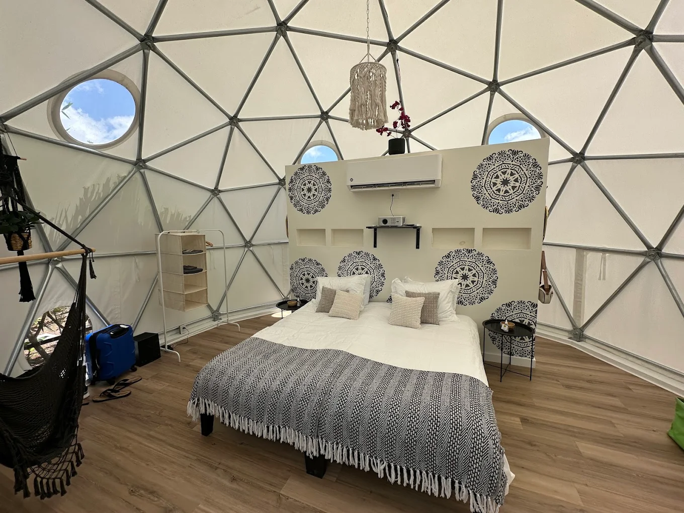 Interior of a glamping dome with a cozy bed and hammock chair